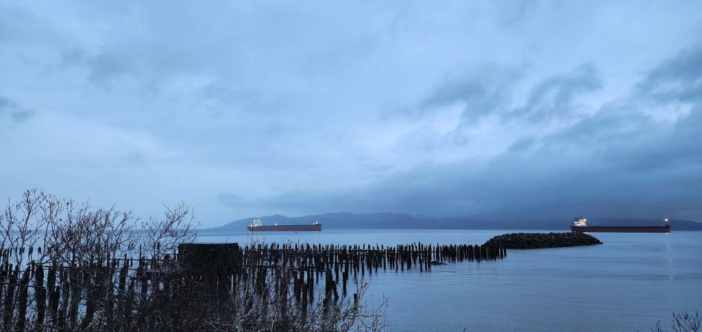 a very blue riverscape with ships in the distance, taken just at evening in the rain
