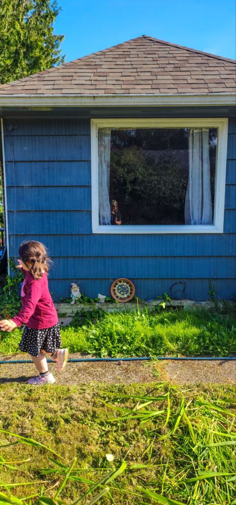 A blurry child runs by the square blue wall of a house