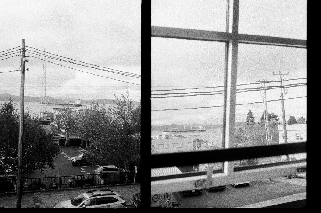 2 black and white photos both views from windows at Fort George in Astoria Oregon. There's a big ship in the river.