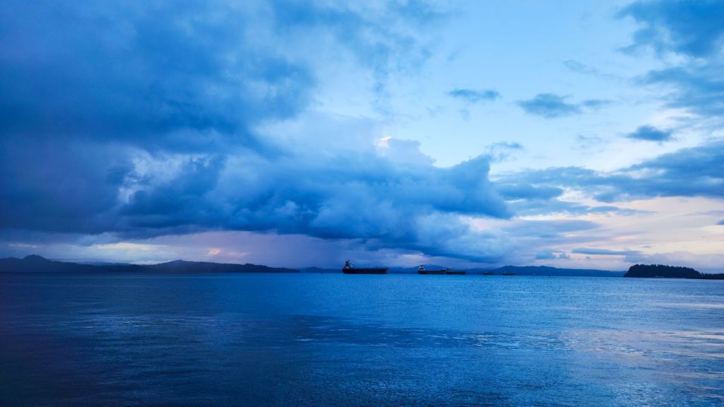 A view of the Columbia River just after sunset; it is very blue and the sky is filled with illuminated heavy clouds
